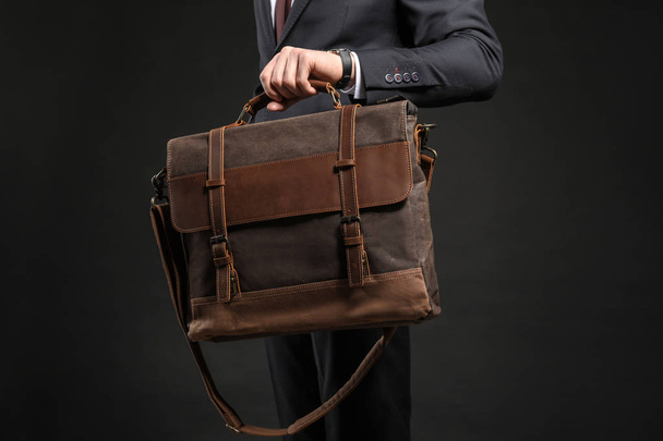 Handsome businessman with stylish briefcase on dark background - Foto, imagen