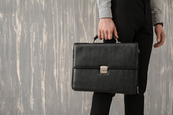 Handsome businessman with stylish briefcase on grey background - 写真・画像
