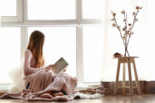 молодая женщина читает книгу у окна
 - Фото, изображение