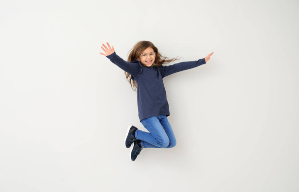 Jumping little girl on white background - Фото, изображение