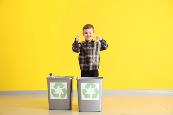 Маленький хлопчик кидає сміття в сміттєві баки біля кольорової стіни. Концепція переробки
 - Фото, зображення