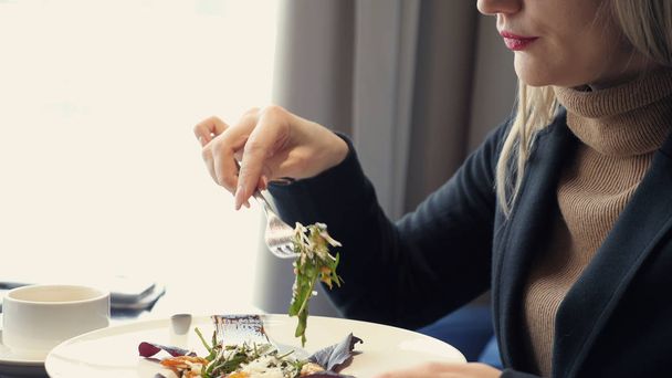 mujer irreconocible comiendo ensalada sentada en la cafetería
 - Foto, imagen