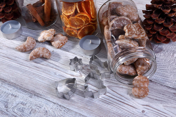 jars of homemade christmas cookies, cinnamon and dried orange slices on grey wooden background - Foto, Imagen