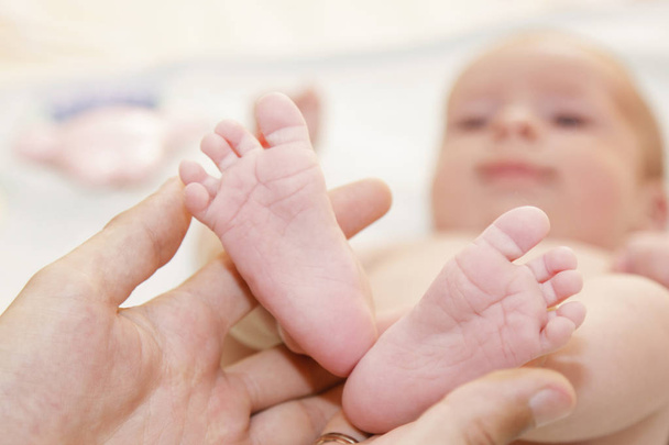 Father holds newborn babys feets. Tiny legs in mans hand - Photo, Image