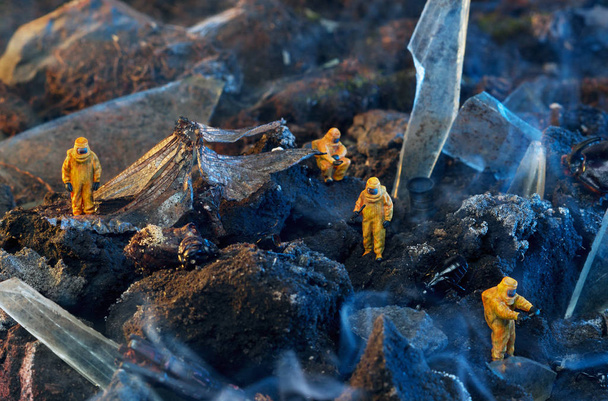 Conceptual photo of toy people in hazmat suits and wings of a dead dragonfly. Environmental disaster concept. - Foto, Imagem