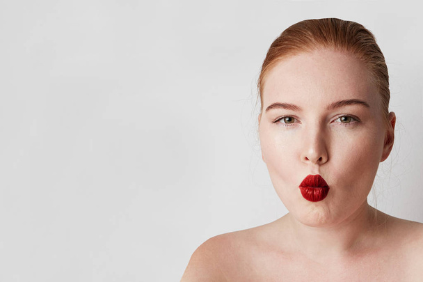 Handsome redhead female model with light nude make-up posing over white background. - Zdjęcie, obraz