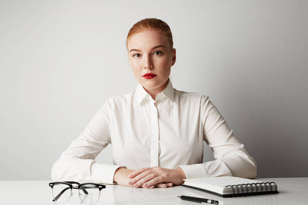 Charming redhead business woman working at the table over empty white background. - Fotó, kép