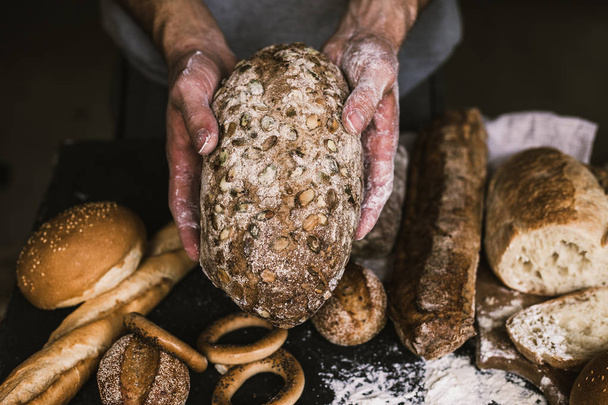 Baker man holding a rustic organic loaf of bread in his hands - Foto, afbeelding