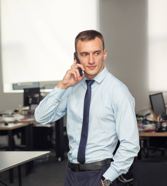 Ofiste bir smartphone cep telefonu ile konuşurken bir iş adamı portresi. Telefonla satış. - Fotoğraf, Görsel