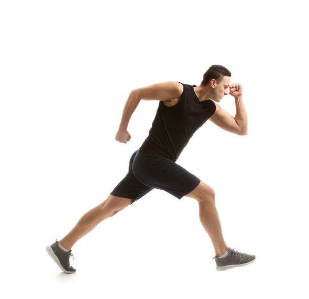 Urheilullinen nuori mies juoksee valkoista taustaa vasten
 - Valokuva, kuva