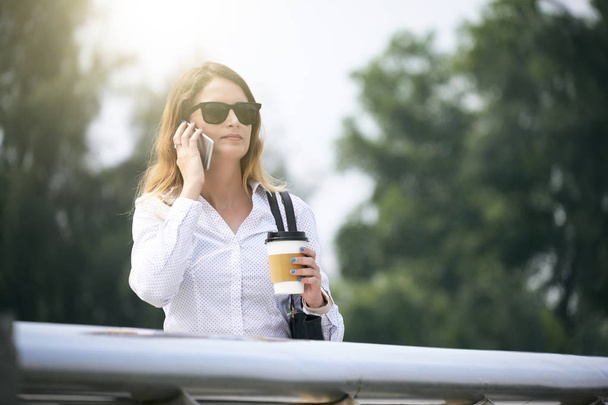 Портрет серйозної бізнес-леді в сонцезахисних окулярах, що розмовляють по телефону
 - Фото, зображення