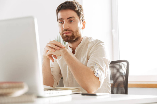 Image of european office guy 30s wearing white shirt using lapto - Фото, зображення