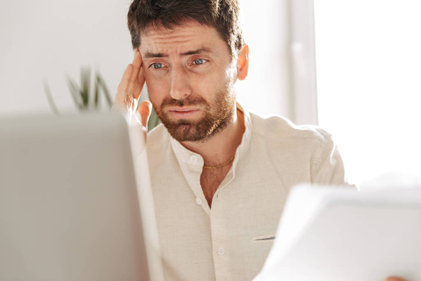 Image of perplexed office worker 30s wearing white shirt using l - Zdjęcie, obraz