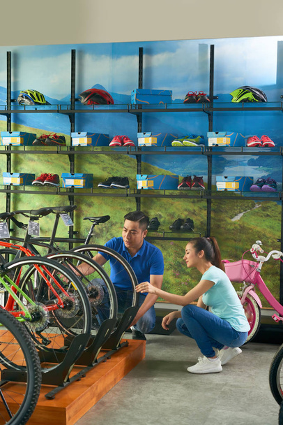 Salesman helping female customer with choosing bicycle - Fotografie, Obrázek