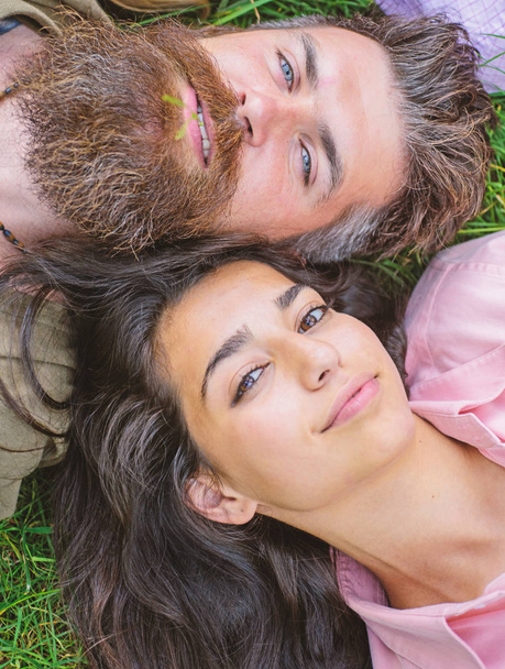 Hipster bearded man and girl happy carefree enjoy relax. Man unshaven and girl lay near top view. Feminine and masculine characters comparison. Couple in love relaxing lay at meadow close up - Photo, image