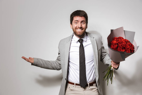 Businessman in formal clothes isolated over white wall background holding flowers. - Foto, imagen