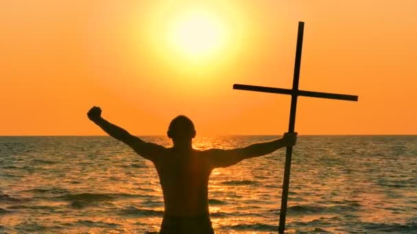 4. gebed man met Christian Kruis tegen mariene oranje zonsondergang of zonsopgang. Achteraanzicht - Video