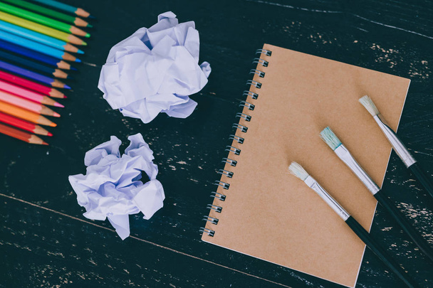 desk with mixed art supplies including coloured pencils notepads - Φωτογραφία, εικόνα