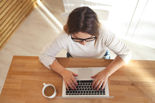 Вид сверху на женские руки, сидящие на клавиатуре ноутбука в очках
 - Фото, изображение
