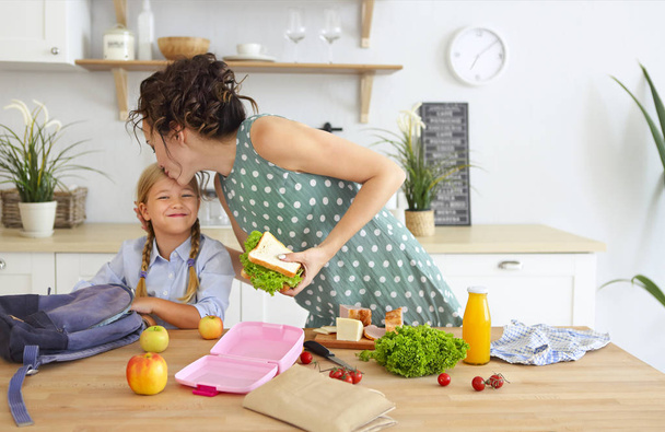 schöne brünette Mutter und ihre Tochter Verpackung gesundes Mittagessen - Foto, Bild