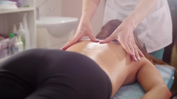 Clínica de belleza Una joven morena recibiendo un masaje de espalda. Vista desde atrás
 - Metraje, vídeo
