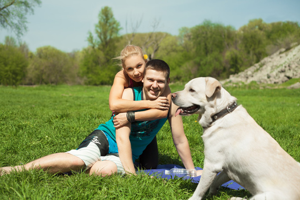 Un jeune couple assis avec un chien dans le parc
 - Photo, image