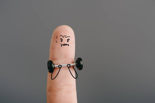 cropped view of finger as sweaty sportsman exercising with barbell isolated on grey - Fotó, kép