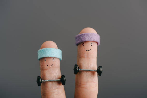 обрезанный вид улыбающихся спортивных пальцев в повязках тренировки с штангой, изолированной на сером
 - Фото, изображение
