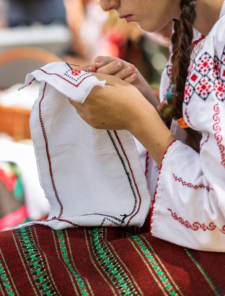 Nuori nainen pukeutunut romanialainen folk port, työskentelee manuaalisesti
 - Valokuva, kuva