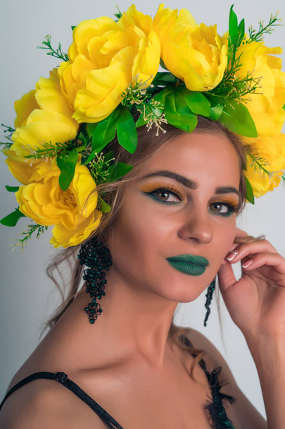 Portrait of a beautiful blonde with bright makeup and a rim of yellow flowers - Fotó, kép