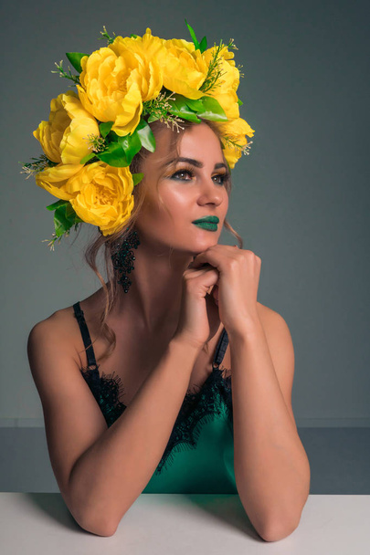 Portrait of a cute beautiful blonde with a rim of yellow flowers and bright makeup on a dark background - Fotografie, Obrázek