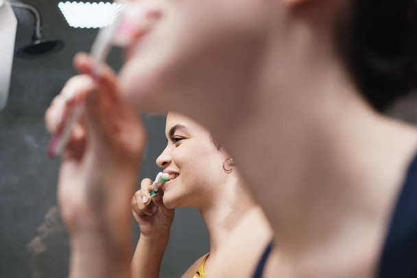 Lesbische vrouwen samenleven tanden poetsen in de badkamer thuis - Foto, afbeelding