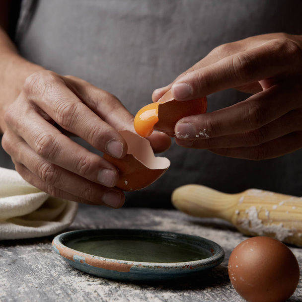 young man separating the yolk of an egg - Zdjęcie, obraz