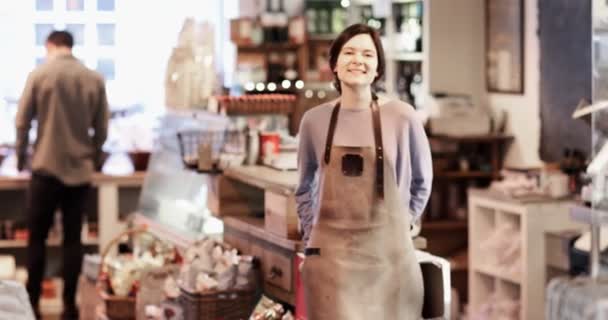エプロンを身に着けているデリカテッセン ショップの女性オーナーの笑顔のポートレート - 映像、動画