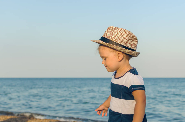 Little girl in a hat walks along the seashore - Фото, зображення