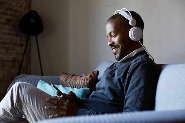 Confident African American man with headphones listening to music on his phone. Concept of relaxation. - Φωτογραφία, εικόνα
