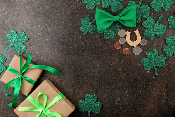 St.Patrick 's Day. celebration. Bow tie, horseshoe, gift boxes and clover on a brown background. view from above. space for text - Φωτογραφία, εικόνα