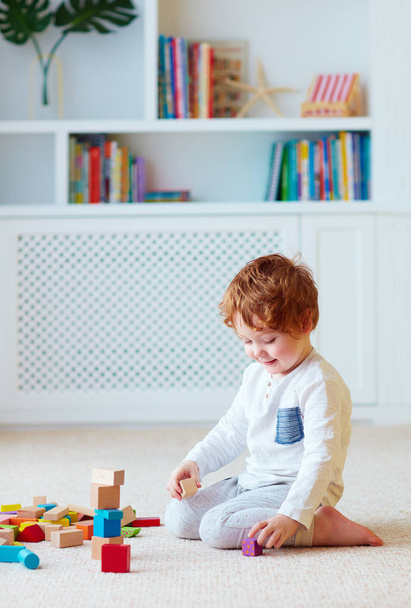 милый малыш малыш играет с деревянными блоками, строит высокую башню
 - Фото, изображение