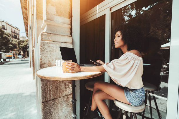 Dizüstü bilgisayar ve telefon ile bir barda kız - Fotoğraf, Görsel