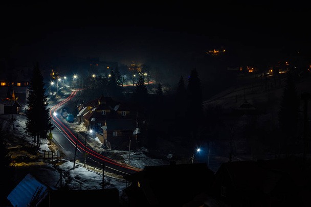 Prachtige nacht landschap van het Oekraïense dorp in fel licht en wazig auto verlichting - Foto, afbeelding