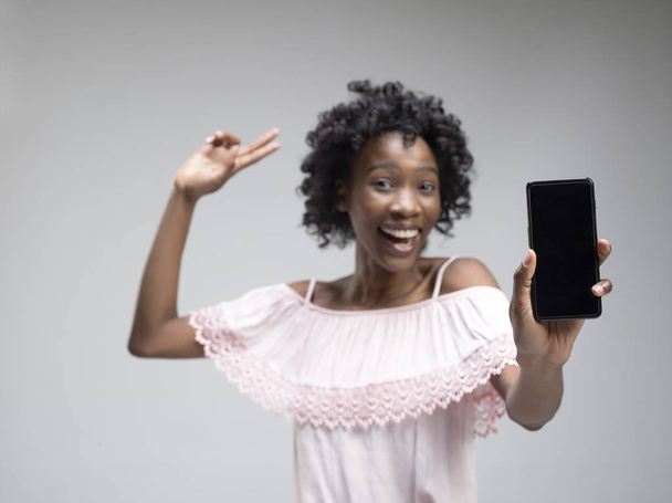 Portrait of a confident casual afro girl showing blank screen mobile phone - Foto, Imagen