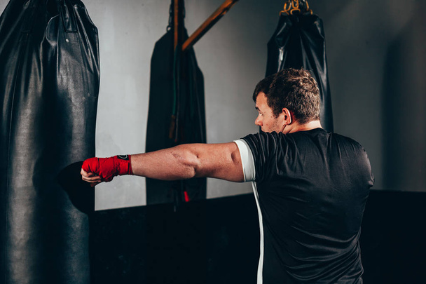 Fighter man training in heavy bag at gym - Фото, зображення