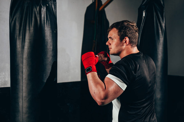 Fighter man training in heavy bag at gym - Фото, изображение