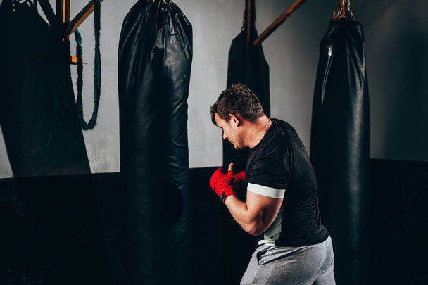 Fighter man training in heavy bag at gym - 写真・画像