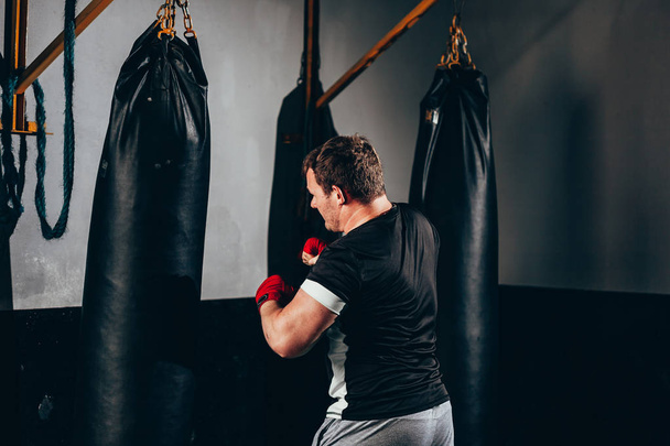 Fighter man training in heavy bag at gym - Foto, Bild