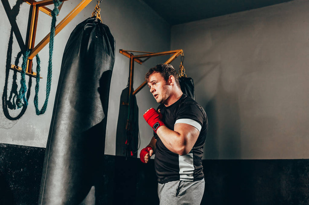 Боец тренируется в тяжелой сумке в спортзале
 - Фото, изображение