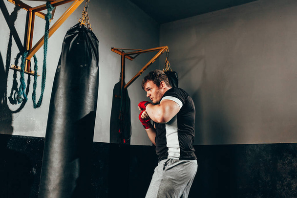 Fighter man training in heavy bag at gym - Foto, afbeelding