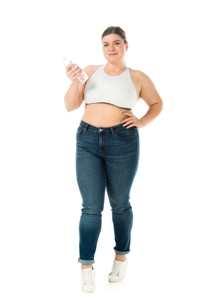 smiling overweight woman in jeans holding bottle with water isolated on white - Photo, Image