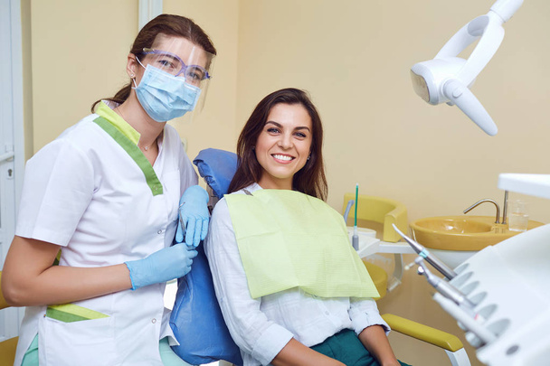 Dentist and female client smiling at the dental clinic - Fotoğraf, Görsel