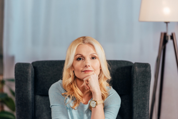 pensive blonde woman looking at camera at home  - Foto, Bild